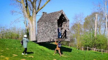 Yüzen Şapel 'in (Zwevende Kapel) fotoğraflarını çeken bir turist. Sanatçı Frits Jeuris 'in küçük ahşap şapeli ve bölgesel manzara Haspengouw, Borgloon Sint-Truiden. Landmark Limburg, Belçika ziyareti, Avrupa seyahati.