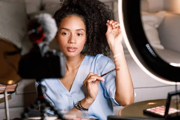 Genç etkileyicinin elinde tonal krem var.