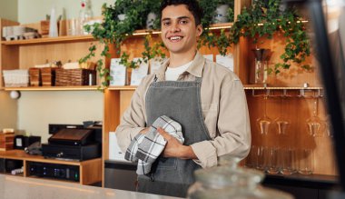 Tezgahta havluyla ellerini silen önlüklü bir barmen.