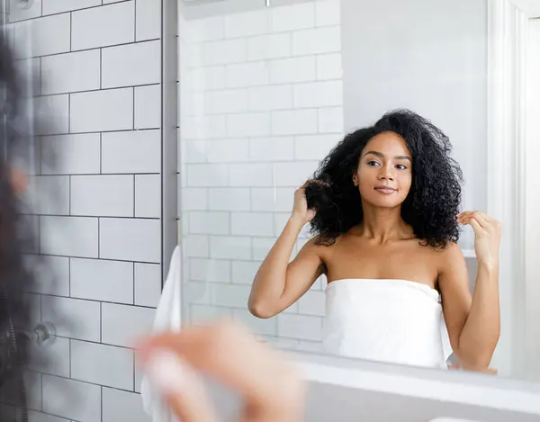 Güzel bir kadın duştan sonra beyaz havluya sarılıp yansımasına bakıyor.