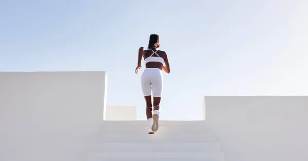 İnce bir bayan sporcunun merdivenlerde koşarkenki dikiz görüntüsü. Merdivenlerde koşan bir kadının arka görüntüsü..