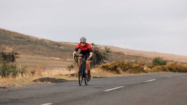 Spor giyim sektöründe profesyonel kadın bisikletçi boş bir yolda pratik yapıyor.