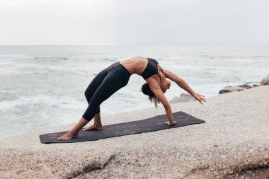Vahşi şey yoga yapan kadın dışarıda poz veriyor. Camatkarasana pozu veren bir kadın..