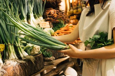 Açık hava pazarında elinde taze taze taze soğan tutan tanınmayan bir kadının elleri.