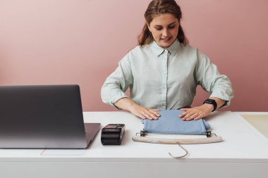 Genç butik sahibi tezgahın üzerindeki kıyafetleri düzeltiyor.