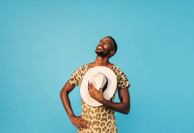 Göğsünde hasır şapka tutan yakışıklı genç adam yukarı bakıyor.