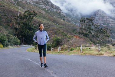 Genç, sıska bir kadının doğal bir parkta sabah yürüyüşü yapması. Kendine güvenen bir kadın yürürken manzaranın tadını çıkarıyor..
