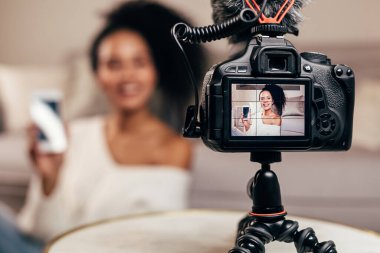 Bir akıllı telefon tutarak bir genç vlogger gösterilen Closeup Dslr fotoğraf makinesi perde