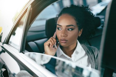 Kadın girişimci takside otururken cep telefonu üzerinde konuşurken