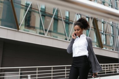 Binada yürürken cep telefonuyla konuşan güzel kadın.