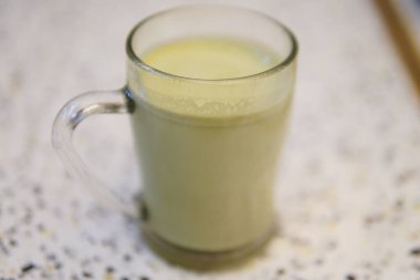 Bir bardak taze süt ve ahşap bir masada yeşil bir smoothie.