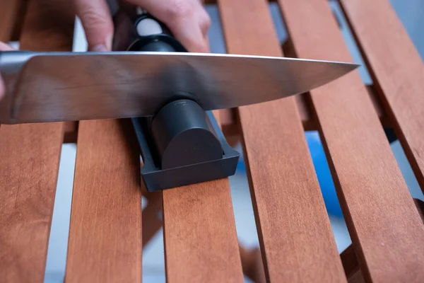 sharpen knives with home knife sharpening tool on wooden table