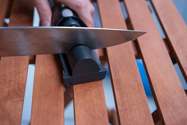 sharpen knives with home knife sharpening tool on wooden table