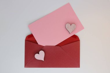 Burgundy open envelope with pink sheet of paper for writing text with hearts decoration