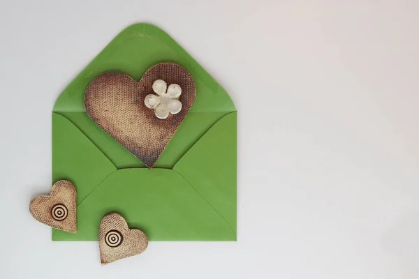 Open green envelope and ceramic hearts, greeting card