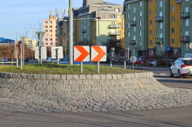 Beyaz zemin üzerinde kırmızı bir ok bulunan trafik işaretli küçük bir kavşak.