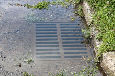 Şiddetli yağmurun altında kalan ve artık içine akmayan bir drenaj kanalı.