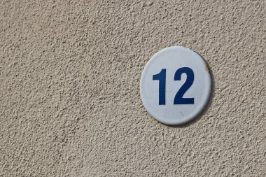 Duvarında 12 numara yazan küçük yuvarlak bir tabela.