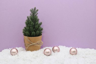 Noel ve Yeni Yıl kartı, ağaç ve Noel baloları süslemesi ve pembe-mor arka planda kar