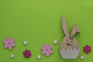 Paskalya kartı, yeşil arka planda Paskalya tavşanı ve bahar çiçekleri.