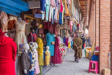 Şimdi, Srinagar, Jammu ve Kashmir, Hindistan. 25 Ekim 2022. Dışarıdaki giyim mağazasının önünden geçen bir adam..