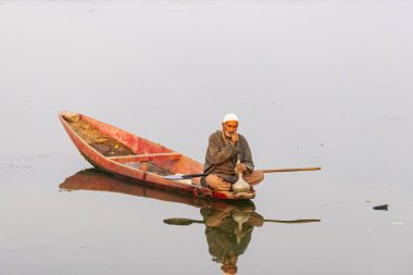 Dal Lake, Srinagar, Jammu ve Kashmir, Hindistan. 26 Ekim 2022. Dal Gölü 'nde geleneksel bir teknede su borusundan sigara içen bir adam..