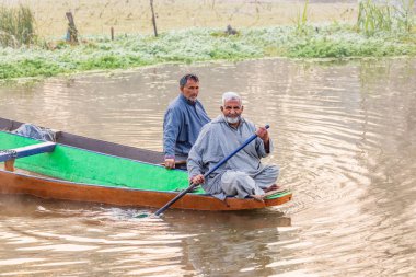 Dal Gölü, Rainawari, Srinagar, Jammu ve Kaşmir, Hindistan. 26 Ekim 2022. Erkekler Dal Gölü 'nde geleneksel bir teknede.