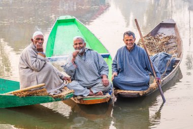 Dal Gölü, Rainawari, Srinagar, Jammu ve Kaşmir, Hindistan. 26 Ekim 2022. Erkekler Dal Gölü 'nde geleneksel bir teknede.