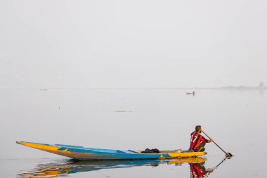 Dal Lake, Srinagar, Jammu ve Kashmir, Hindistan. 26 Ekim 2022. Adam Dal Gölü 'nde geleneksel bir teknede kürek çekiyor..