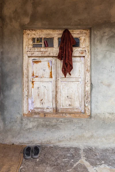 Khansahib Tehsil, Jammu ve Kaşmir, Hindistan. Ahşap bir pencerenin üzerindeki beyaz boya soyuluyor..