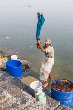 Hazratbal, Srinagar, Jammu ve Kashmir, Hindistan. 30 Ekim 2022. Dal Gölü kıyısında çamaşır yıkayan bir adam..