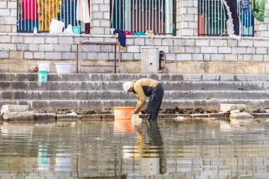 Srinagar, Jammu ve Kashmir, Hindistan. 1 Kasım 2022. Dal Gölü kıyısında çamaşır yıkayan bir adam..