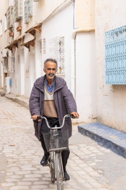 Kairouan, Tunus. 14 Mart 2023. Kairouan şehrinde bisiklet süren bir adam..