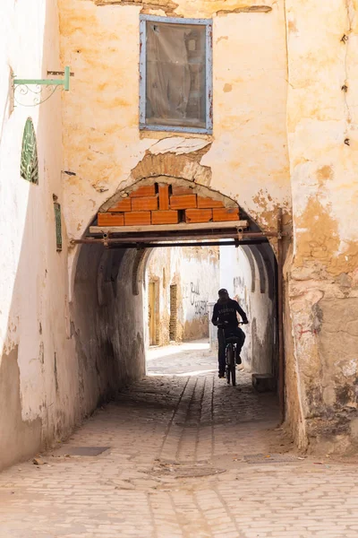 Kairouan, Tunus. 14 Mart 2023. Bisikletle bir geçitten geçerek bir binaya girmek..