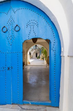 Houmt Souk, Djerba, Medenine, Tunus. 16 Mart 2023. Mavi bir Fas kemer kapısında küçük bir giriş..