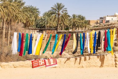 Tozeur, Tunus. Tunus köyündeki bir hatta asılı renkli kumaşlar..