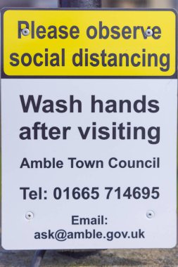 Amble, Morpeth, Northumberland, England, Great Briton, United Kingdom. May 1, 2022. Sign asking visitors to wash their hands and observe social distancing. clipart