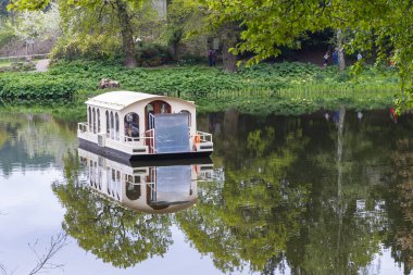 Harewood, Leeds, West Yorkshire, England, Great Briton, United Kingdom. May 2, 2022. Tourist boat in a pond at Harewood House, an 18th Century Treasure House. clipart