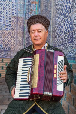 Khiva, Xorazm Region, Uzbekistan, Central Asia. August 22, 2021. Uzbek musician with an accordian in Khiva. clipart