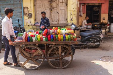 Pushkar, Rajasthan, Hindistan. 7 Kasım 2022. Pushkar pazarında renkli bileziklerle dolu el arabası olan bir satıcı..