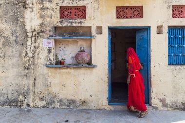 Devnagar, Ajmer, Rajasthan, Hindistan. 8 Kasım 2022. Kırmızılı kadın açık kapıdan içeri bakıyor..