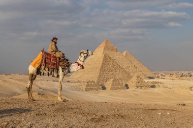 Giza Piramit Kompleksi, Al Ahram, Giza, Mısır. 21 Şubat 2023. Büyük Piramit olarak da bilinen Menkaure, Khafre ve Khufu piramitlerinin önündeki devenin üzerindeki adam..