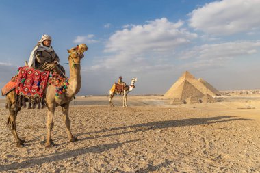 Giza Piramit Kompleksi, Al Ahram, Giza, Mısır. 21 Şubat 2023. Büyük Piramit olarak da bilinen Menkaure, Khafre ve Khufu Piramitleri 'nin önündeki develerin üzerindeki adamlar..