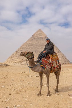 Giza Piramit Kompleksi, Al Ahram, Giza, Mısır. 22 Şubat 2023. Khafre Piramidinin önündeki devenin üzerindeki adam..