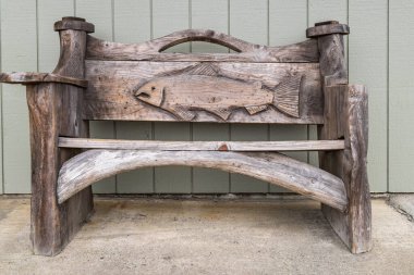 Kuzey Amerika, ABD, Washington Eyaleti, Long Beach. 25 Ağustos 2022. Ağaç dallarından yapılmış ahşap bir bank oyulmuş somonla süslenmiş..