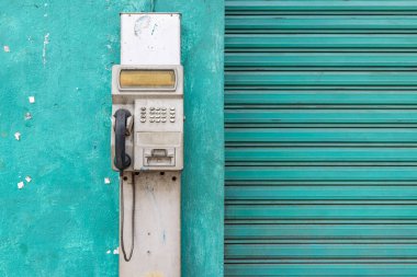 Santiago Atitlan, Solola, Guatemala. Pay phone outside on a green aqua wall. clipart