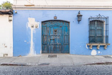 Antigua Guatemala, Sacatepequez, Guatemala. 10 Mart 2024. Antigua Guatemala 'da bir kaldırım taşı caddesinde mavi boyalı ev.