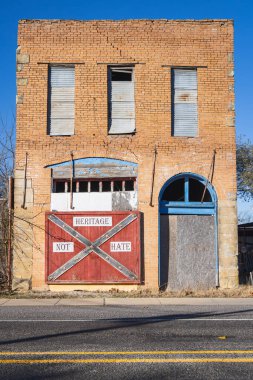 Montague, Texas, United States. December 1, 2024. Boarded up building with a Confederate battle flag labeled Heritage Not Hate, in rural Texas. clipart