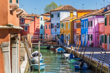 İtalya, Burano. Kanal ve adanın bilinen renkli binaları. Kanal boyunca demirleme direkleri.