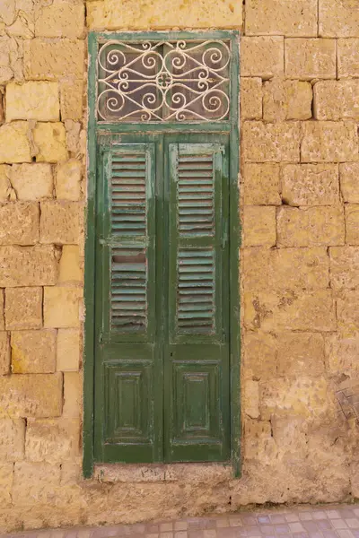 Malta, Birgu. Taş duvardaki yeşil kepenkli kapı.